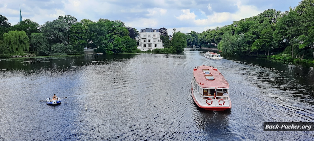 Hamburger Alsterschiff fährt durch die grünen Kanäle im Hamburger Norden, eine der idyllischsten Bootstouren in Hamburg