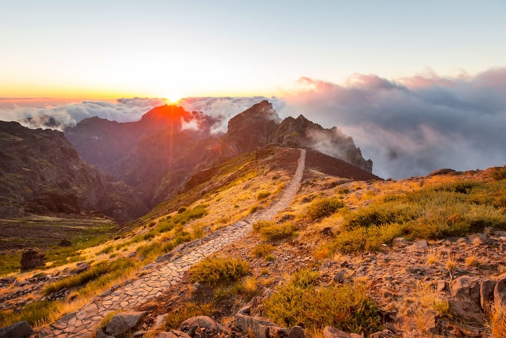 Wanderweg auf einem wolkenverhangenen Berggipfel in Madeira bei Sonnenaufgang