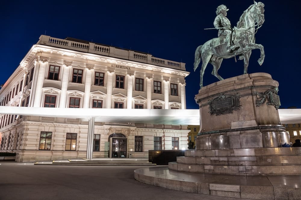 Blick auf das Albertina Gebäude bei Nacht mit Reiterstatue im Vordergrund
