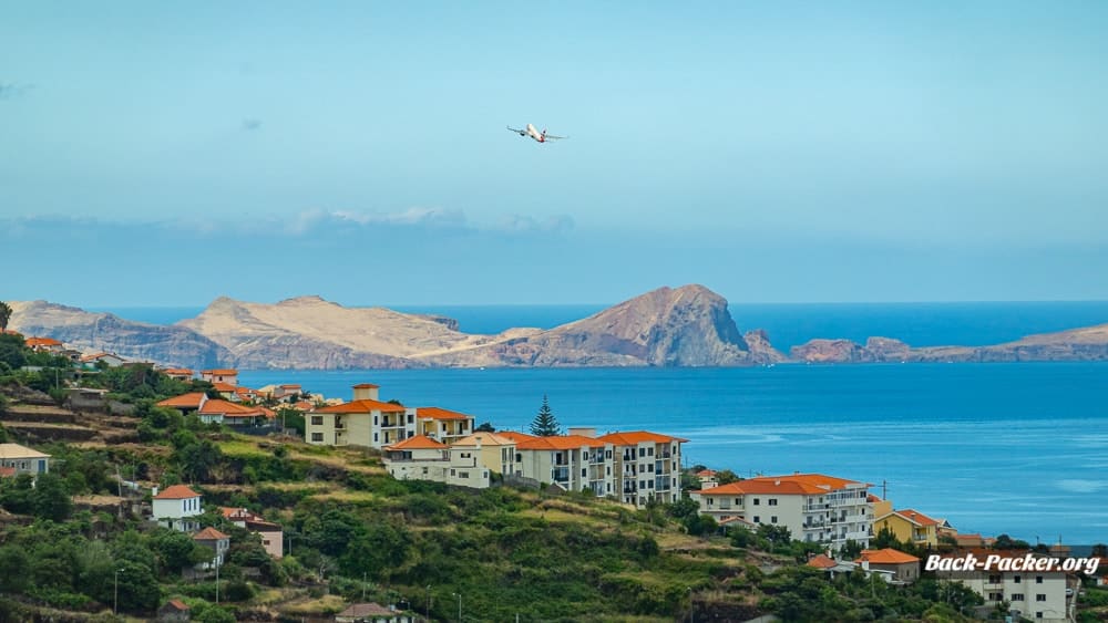Ein Flugzeug hebt vom Inselflughafen ab, im Hintergrund ist die Nachbarinsel zu erkennen.
