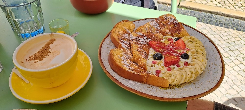 a big cup of chai latte and a plate with french toast and fruits at nicolau
